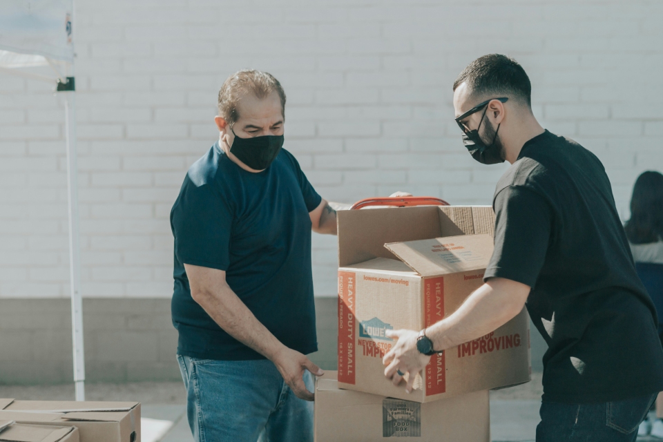 2 moving workers holding cardboard boxes and packing them