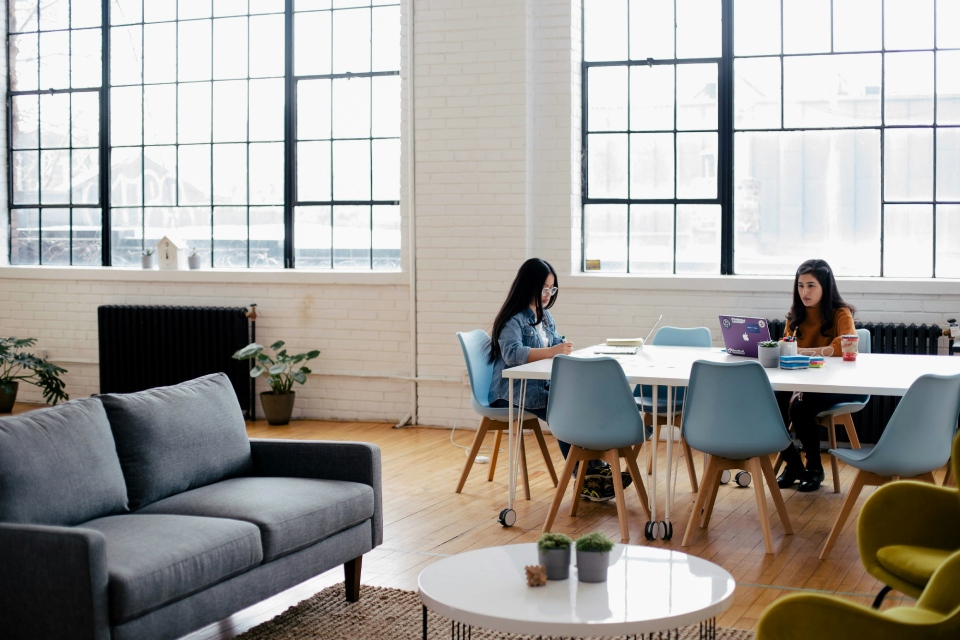 2 professional ladies working on their laptops in an open space